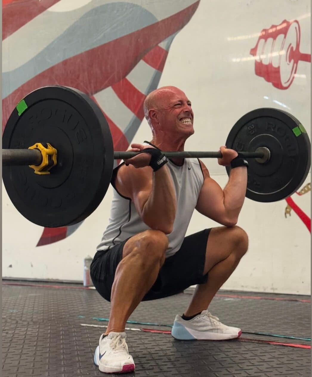 A member front squatting a barbell in front of the Erie Shore mural